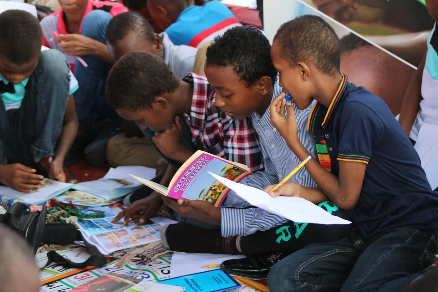 Grupo de crianças sentadas no chão, lendo livros juntas